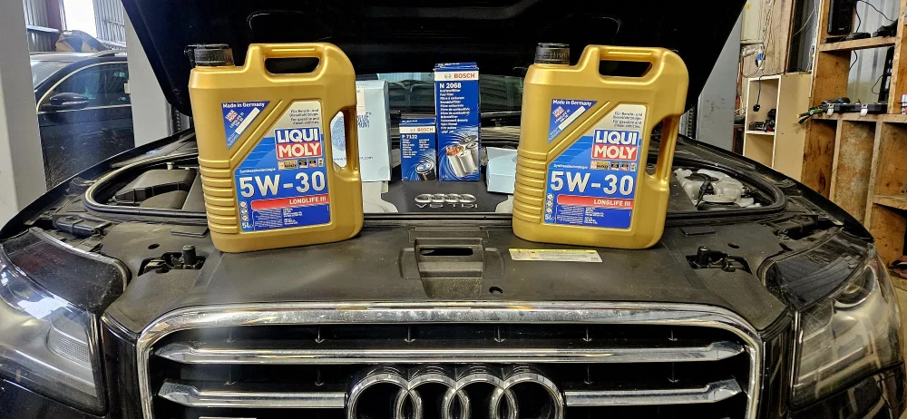 Engine Servicing Diagnostic - Two bottles of motor oil sitting on the hood of a car